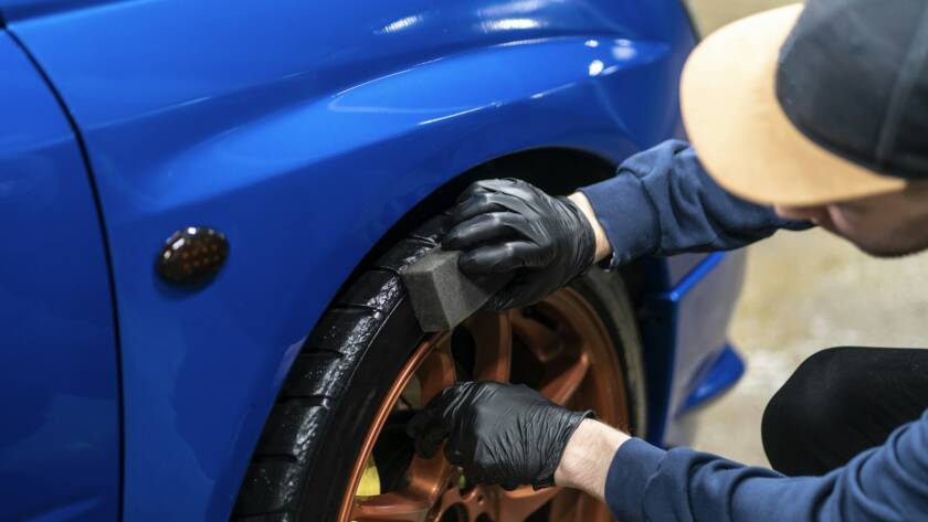 applying a black car tire polish on the wheels
